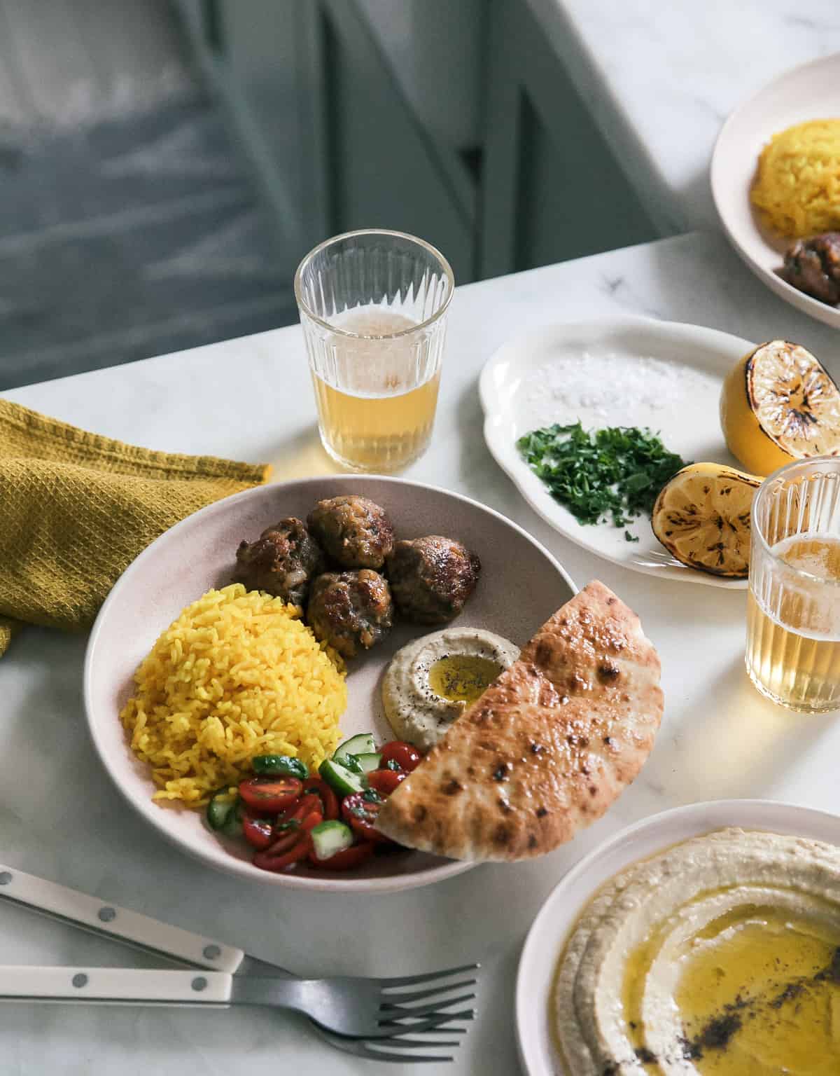 lamb kofta spread with hummus, pita, salad and yellow rice