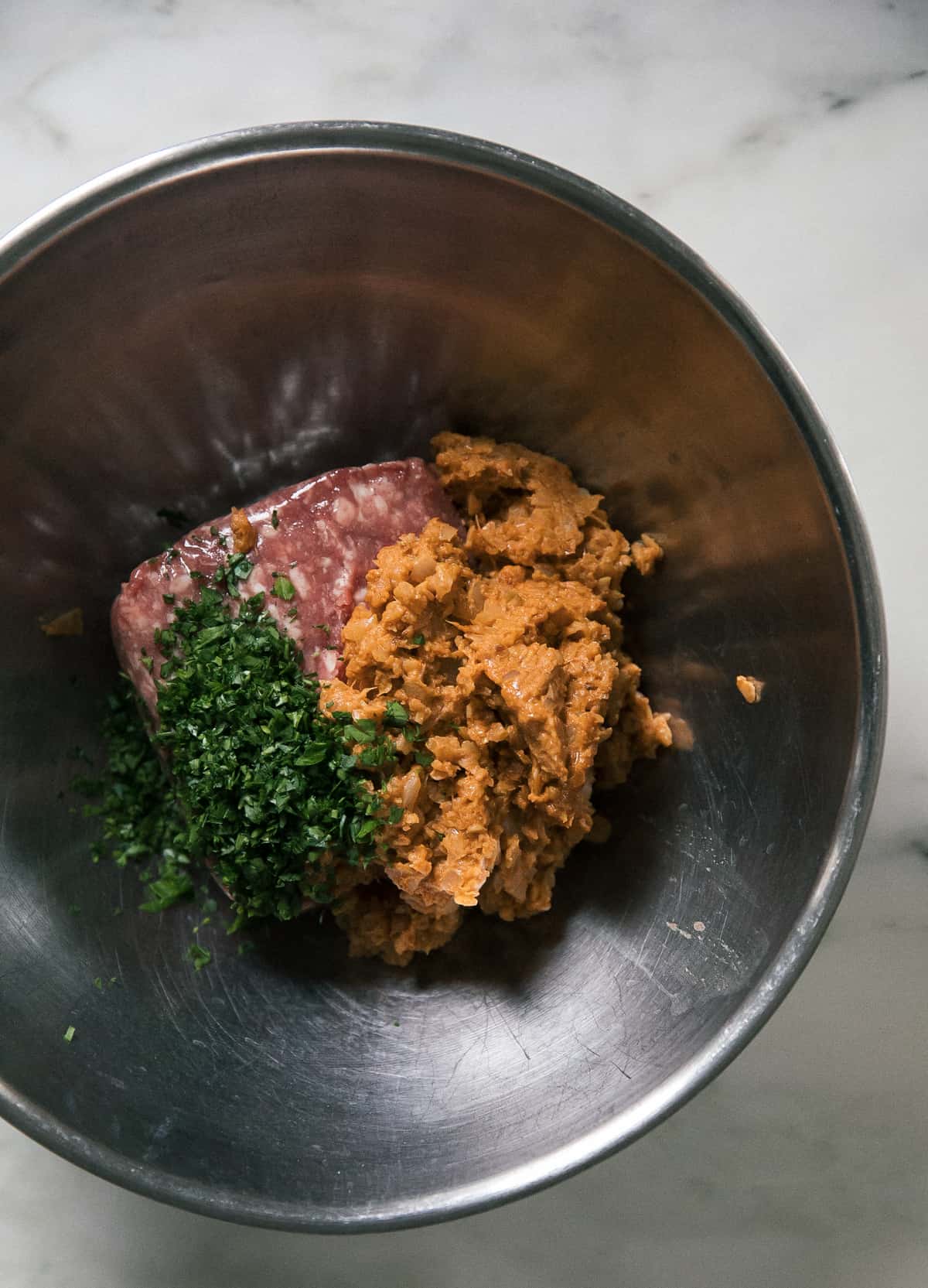 bowl with ground lamb meat, spice mixture and italian parsley