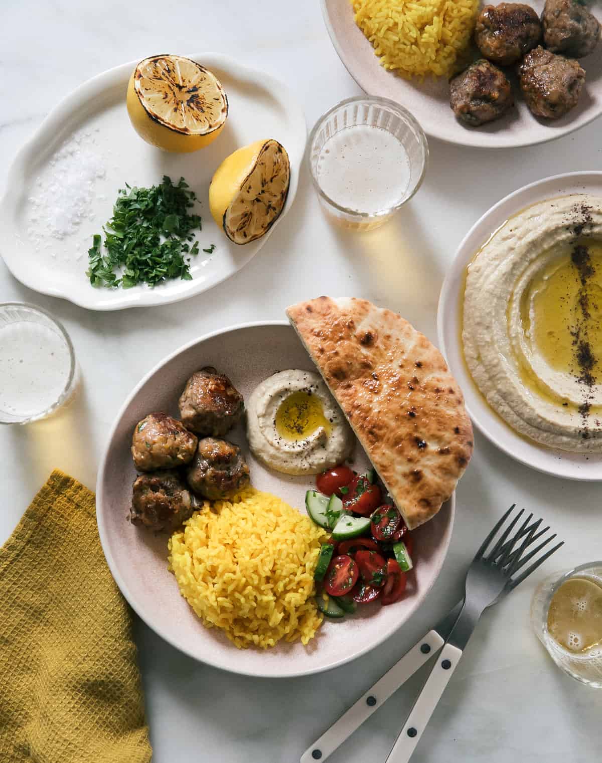 Lamb kofta spread with hummus, pita, salad and yellow rice.