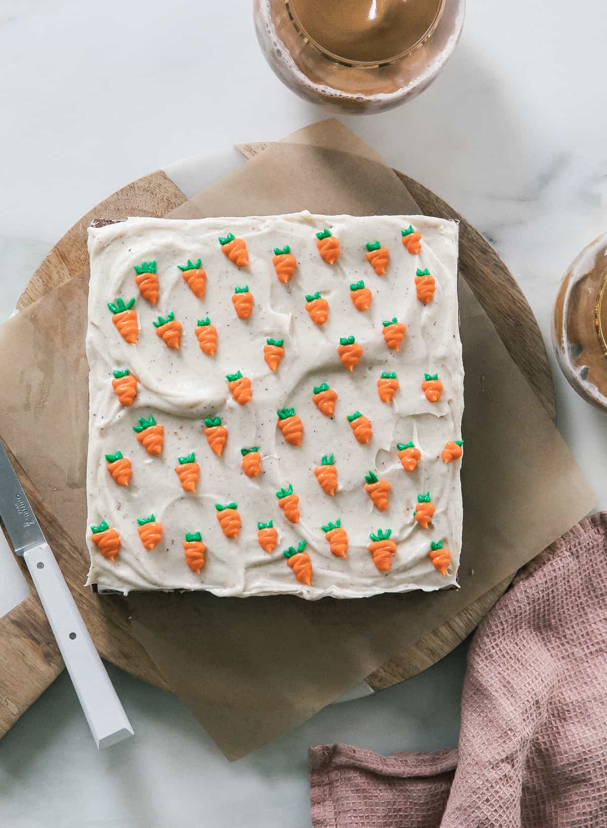 Carrot cake topped with piped on carrots on a cutting board