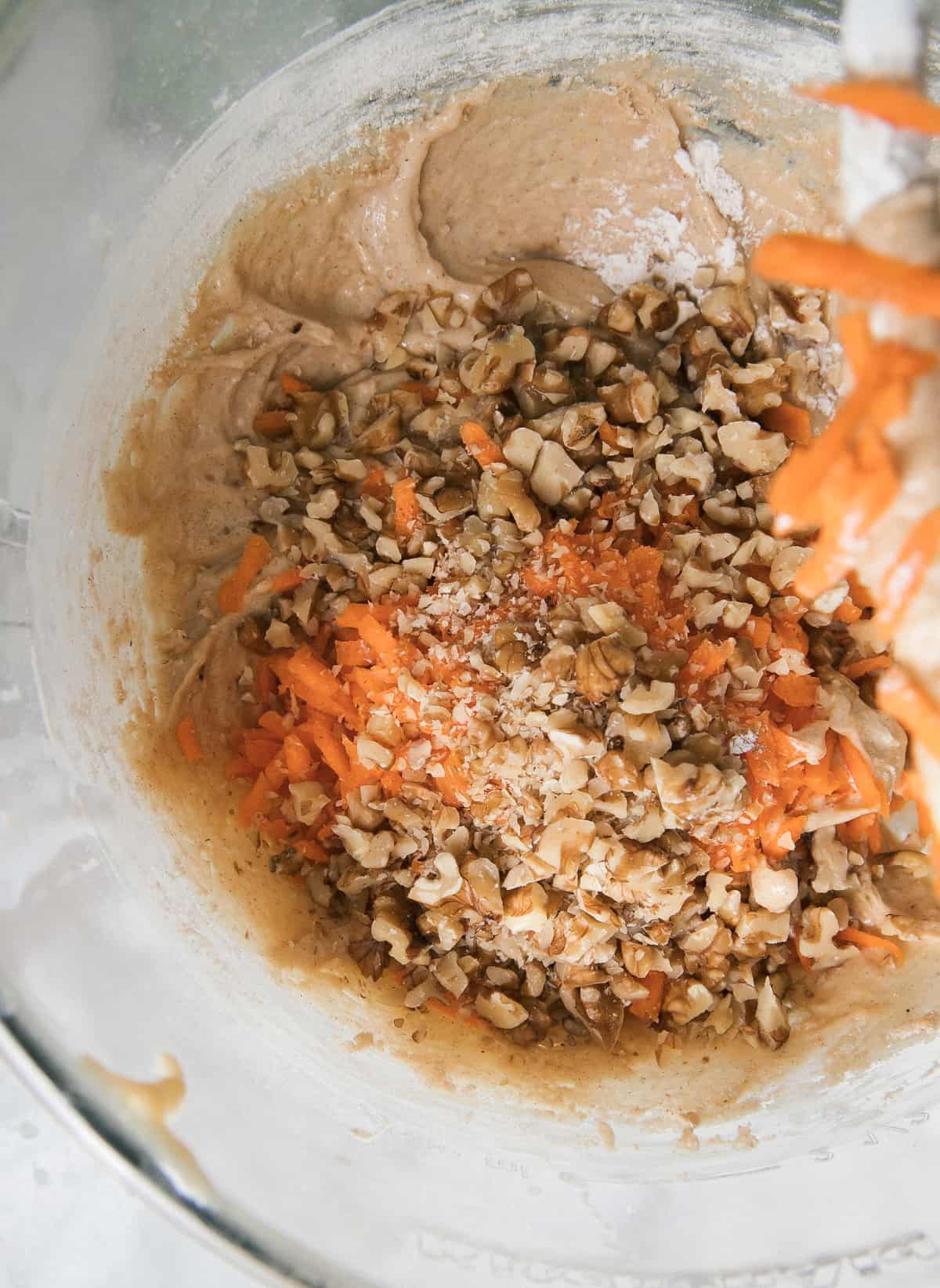 Close up of added nuts and carrots into batter