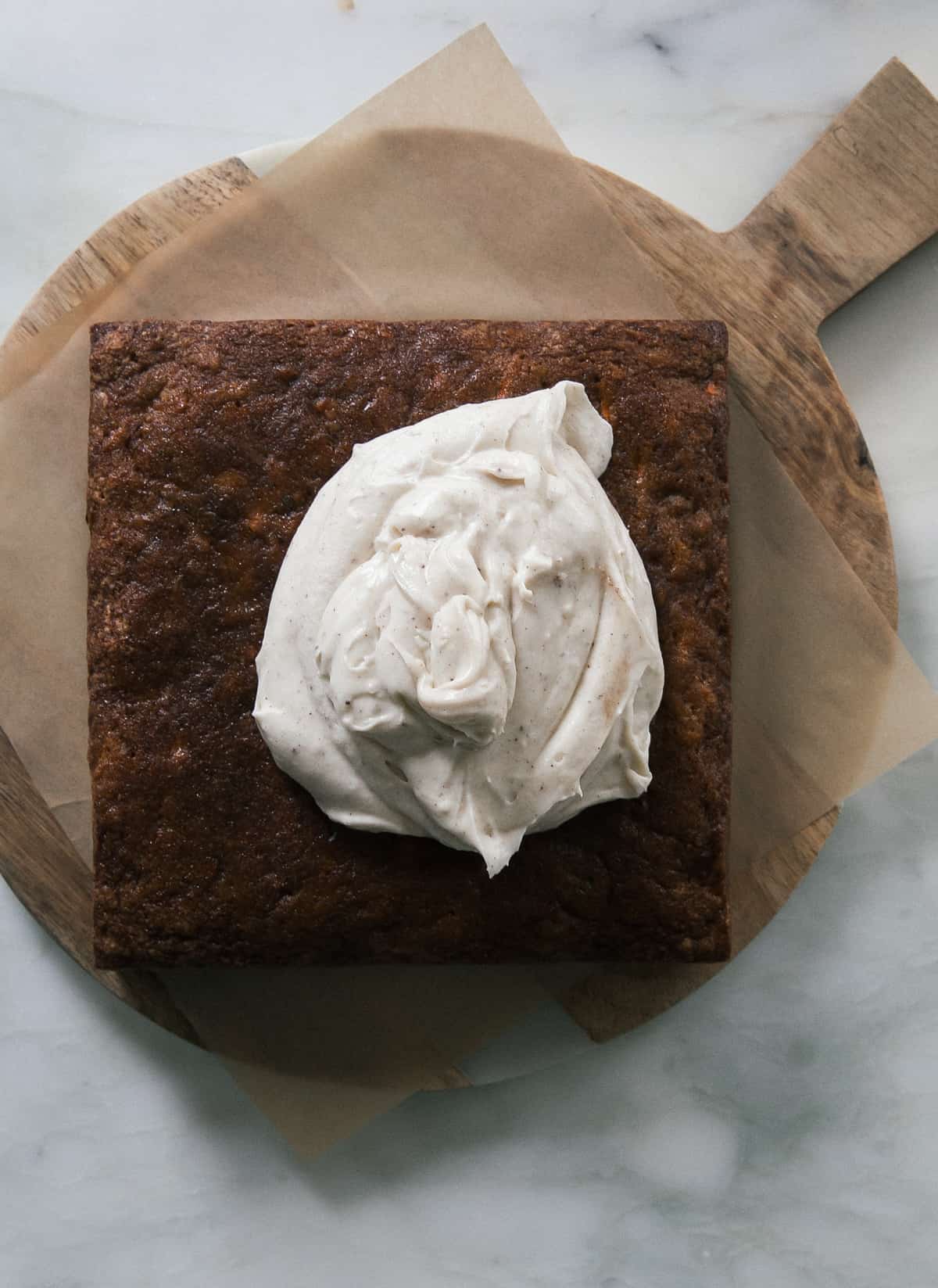 Carrot cake topped frosting on a cutting board