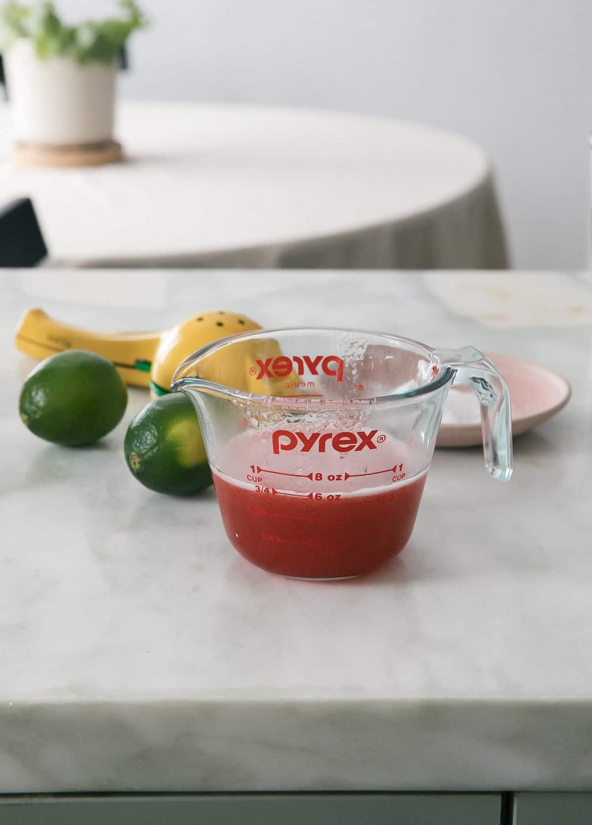 Strawberry syrup in a measuring cup.