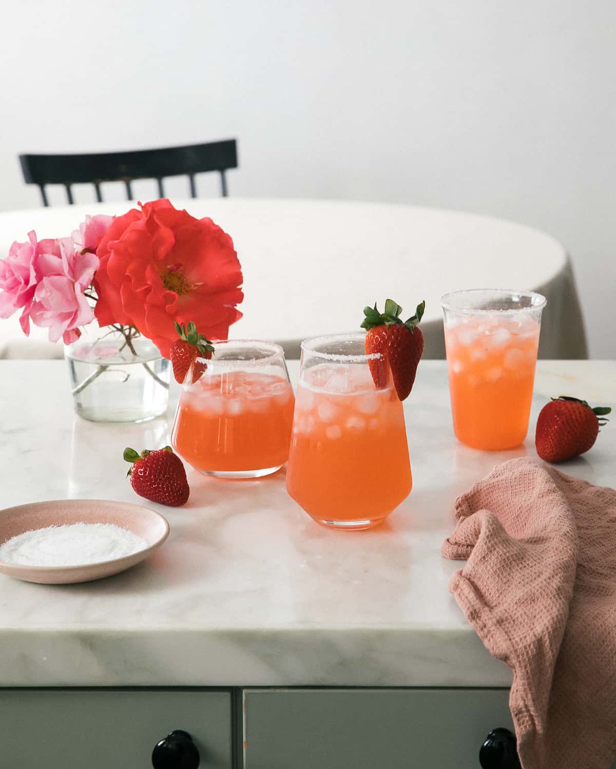 Glasses of strawberry margaritas with strawberries and flowers.