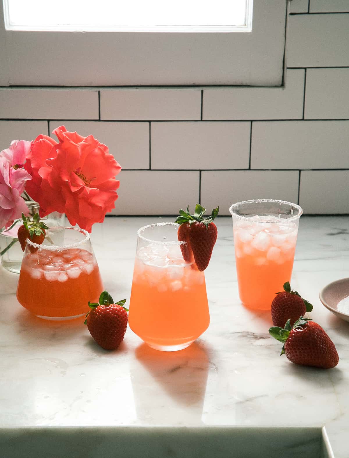 Glasses of strawberry margaritas with strawberries and flowers.