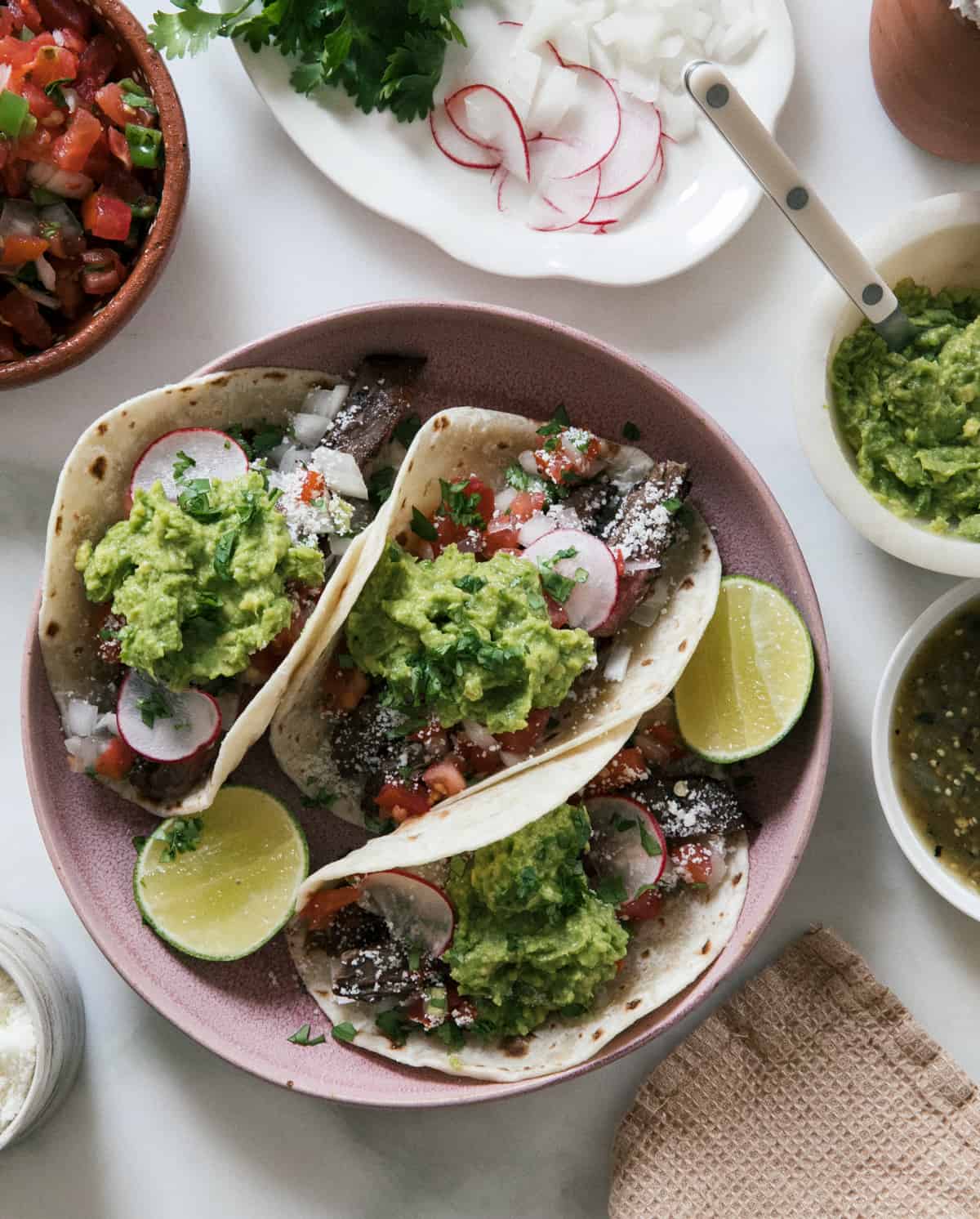 Carne Asada Tacos in bowl with guacamole, cotija cheese, radishes. 