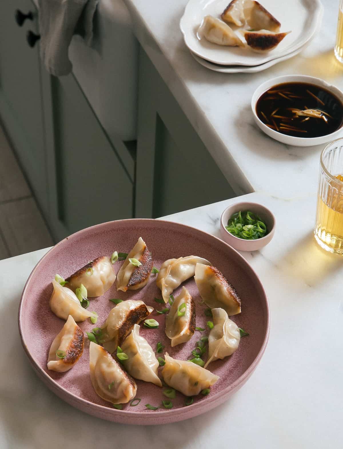 Potstickers on a plate with beer and dipping sauce.