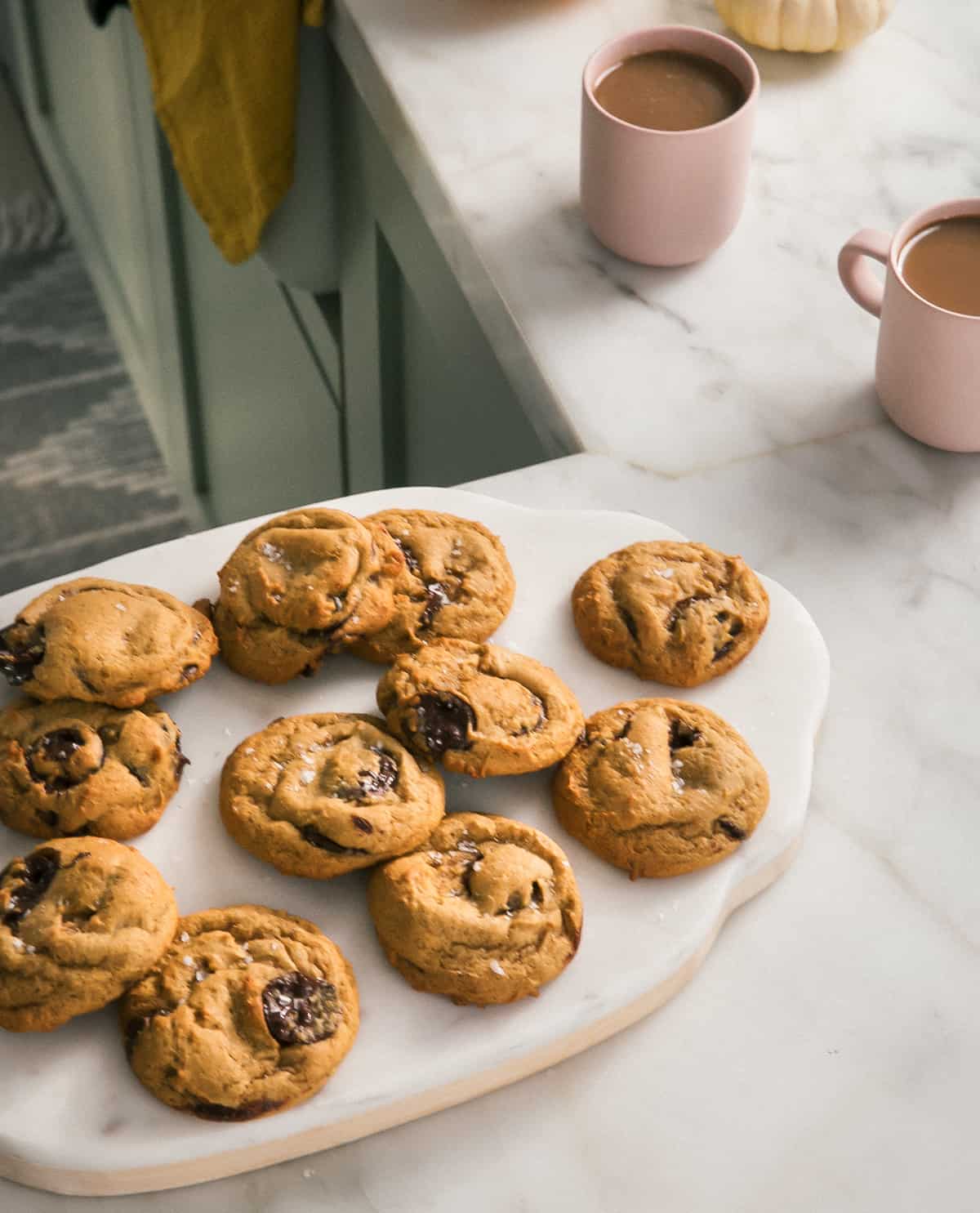 Pumpkin Chocolate Chip Cookies on a cutting board with coffees.