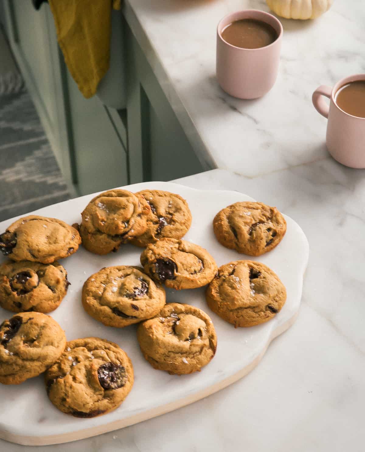 Pumpkin Chocolate Chip Cookies on a cutting board with coffees. 