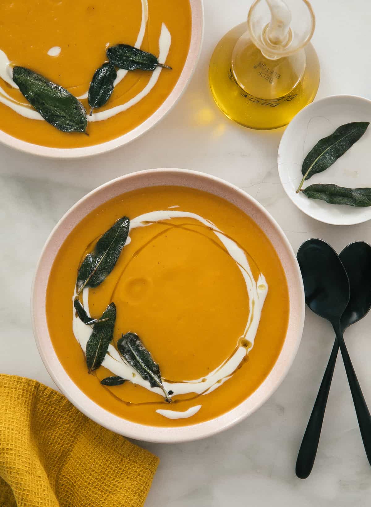 Acorn squash soup in a bowl with spoons on the side. 