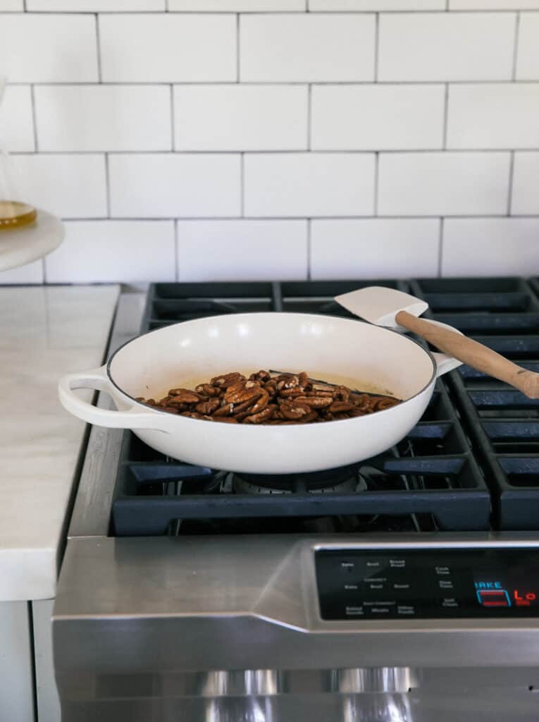 Pecans being toasted in vanilla and butter in a pan. 