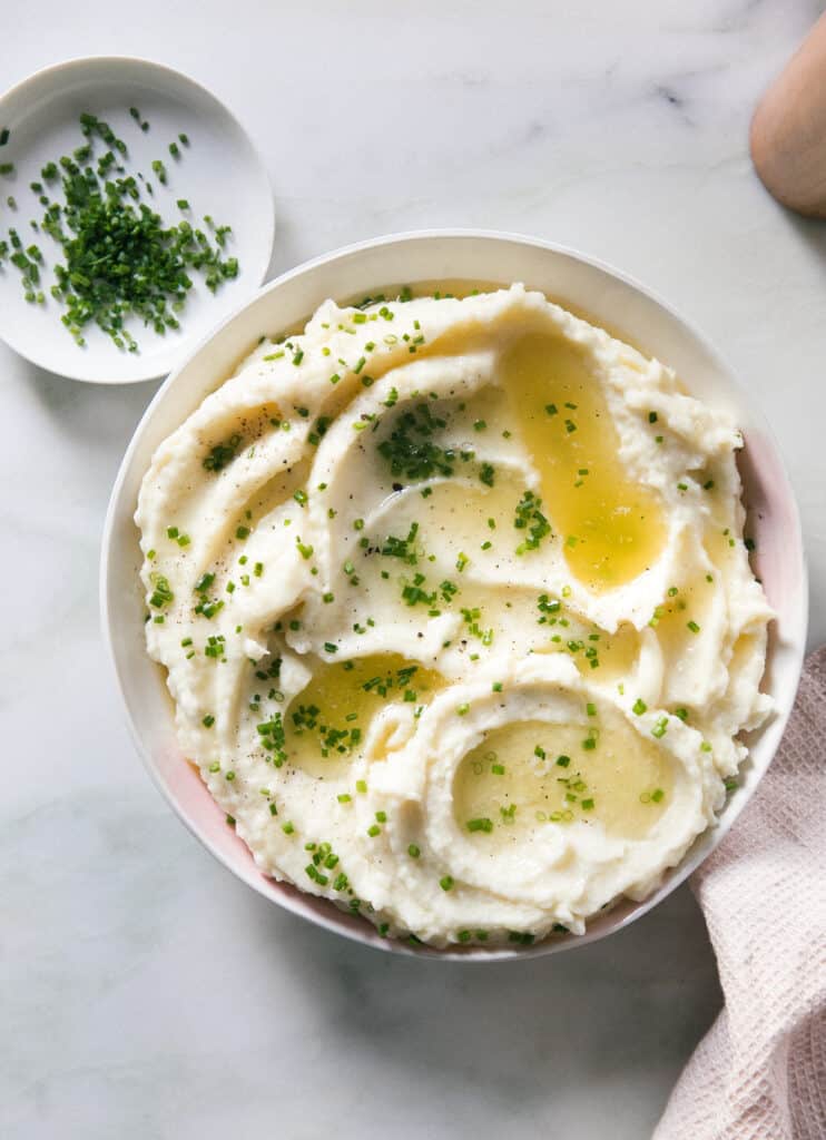 Bowl of creamy mashed potatoes with chives on top. 