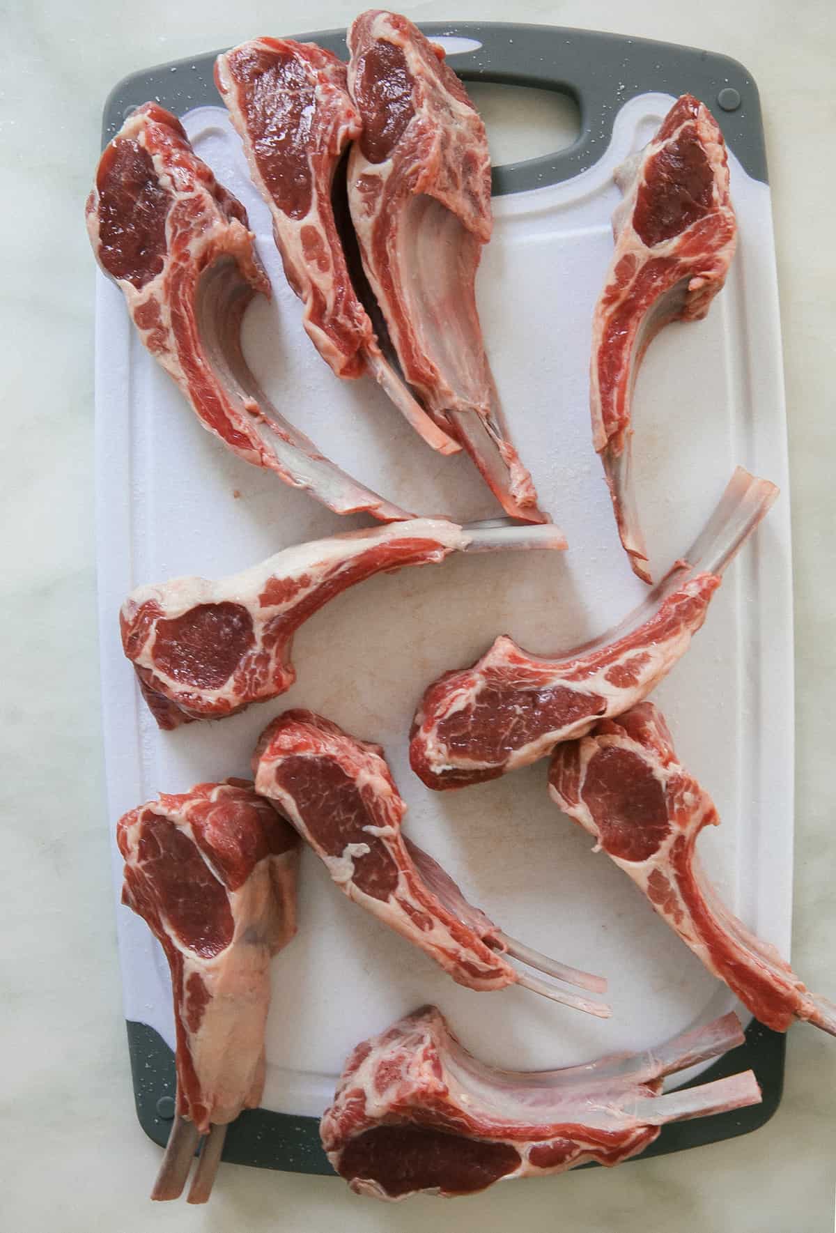 Raw lamb chops on cutting board.