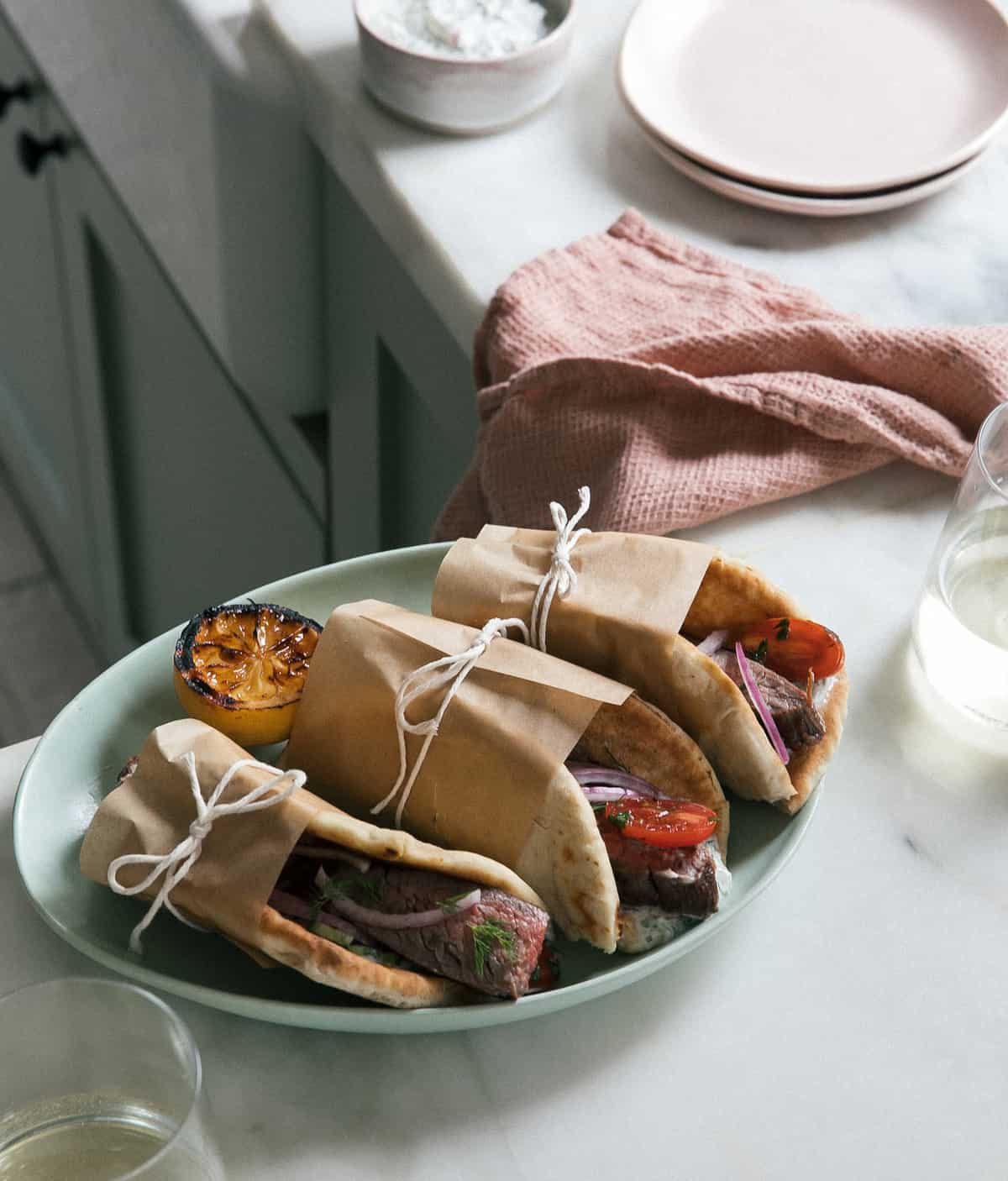 Steak Gyros on a plate with wine on the side. 