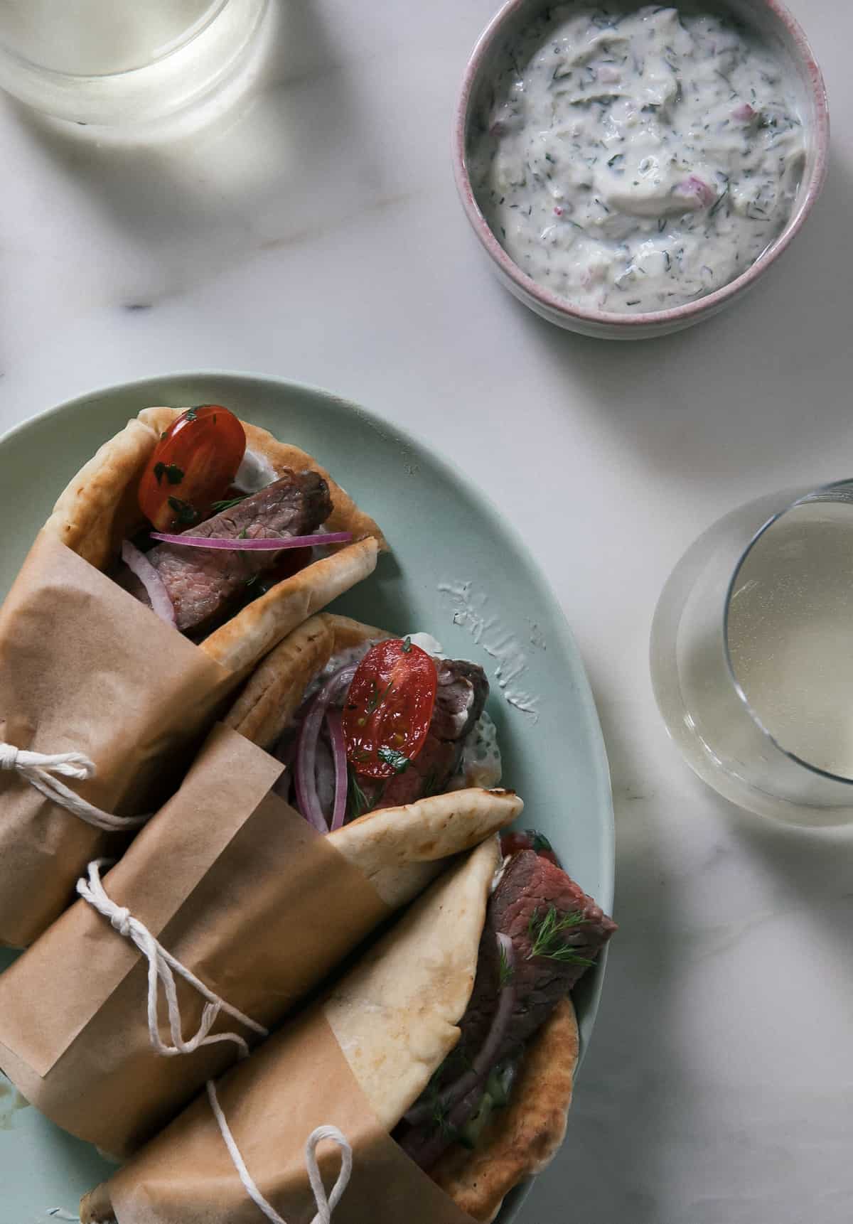 Steak Gyros in pitas with tzatziki and a glass of wine. 