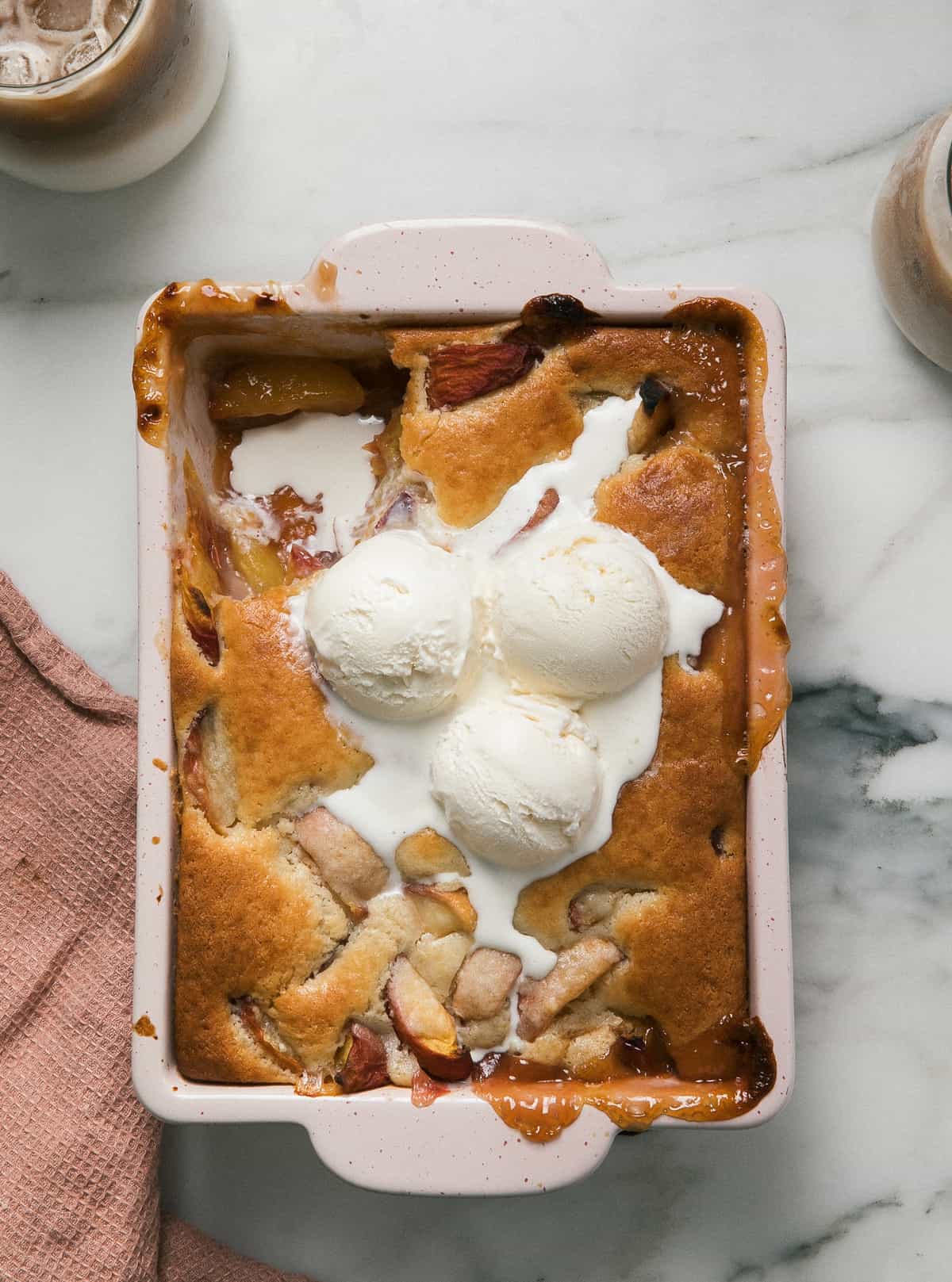Easy Peach Cobbler in baking dish with ice cream.