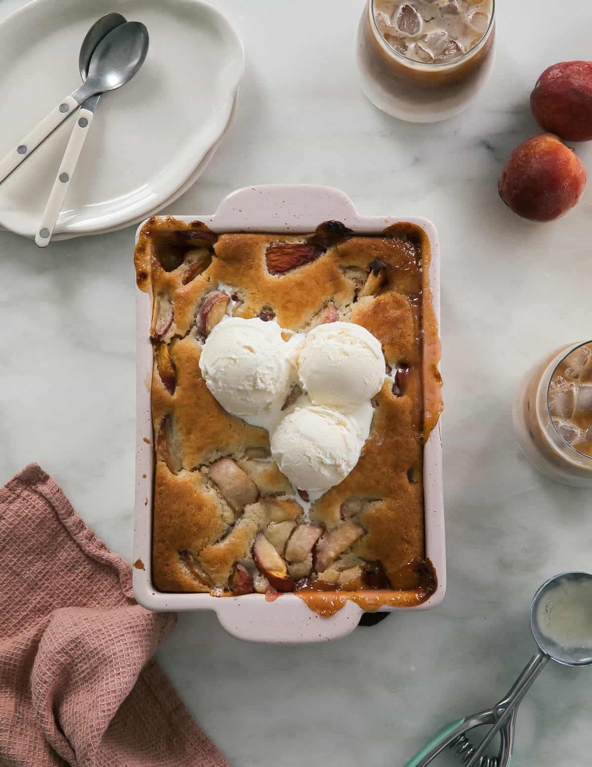 Easy Peach Cobbler in baking dish with ice cream. 