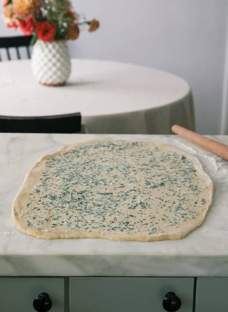 Garlic butter being rubbed on dough. 