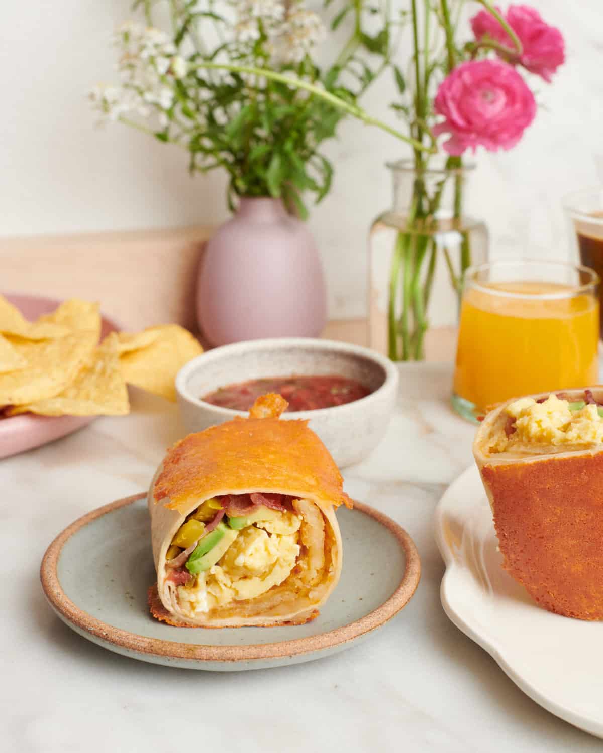 Breakfast Burritos on a plate with salsa and orange juice.