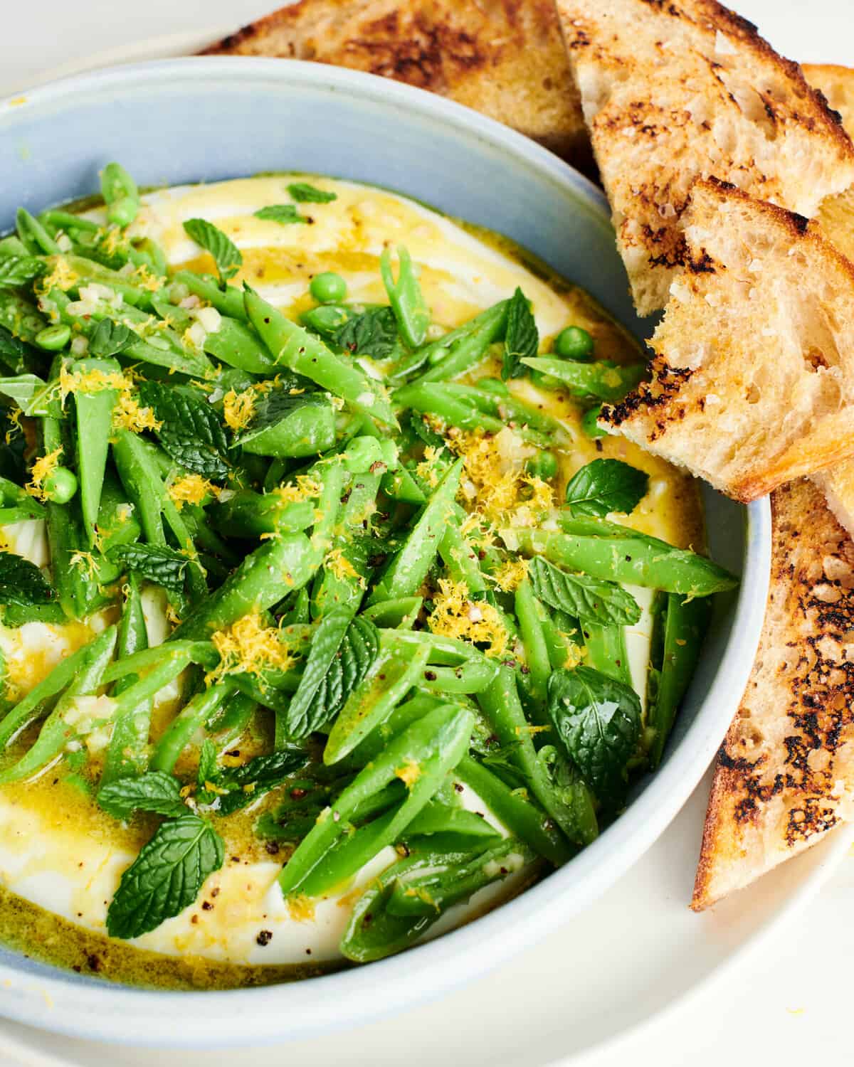 Whipped Feta Dip with Sugar Snap Peas on top with bread. 