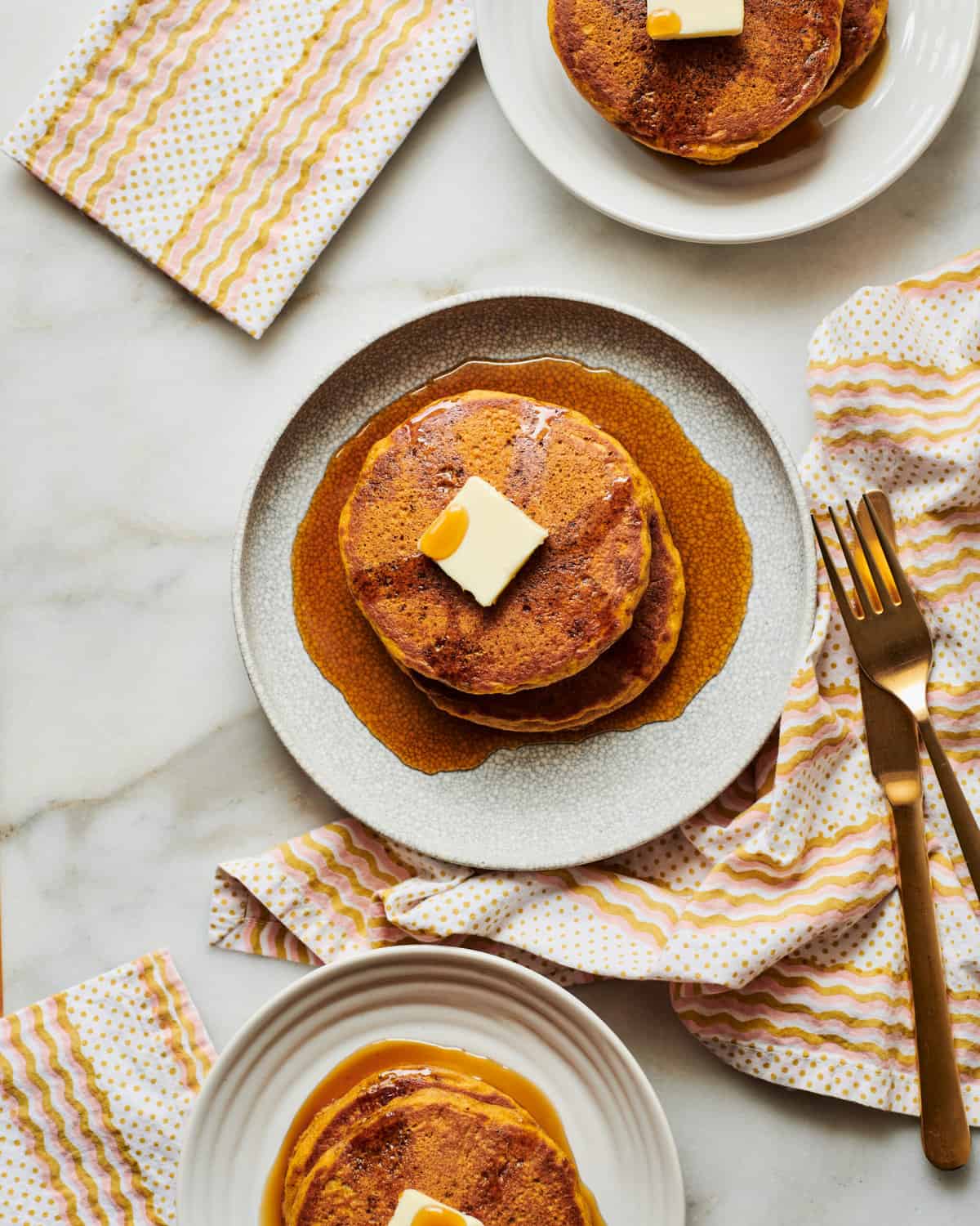 Pumpkin pancakes on a plate with syrup and butter.