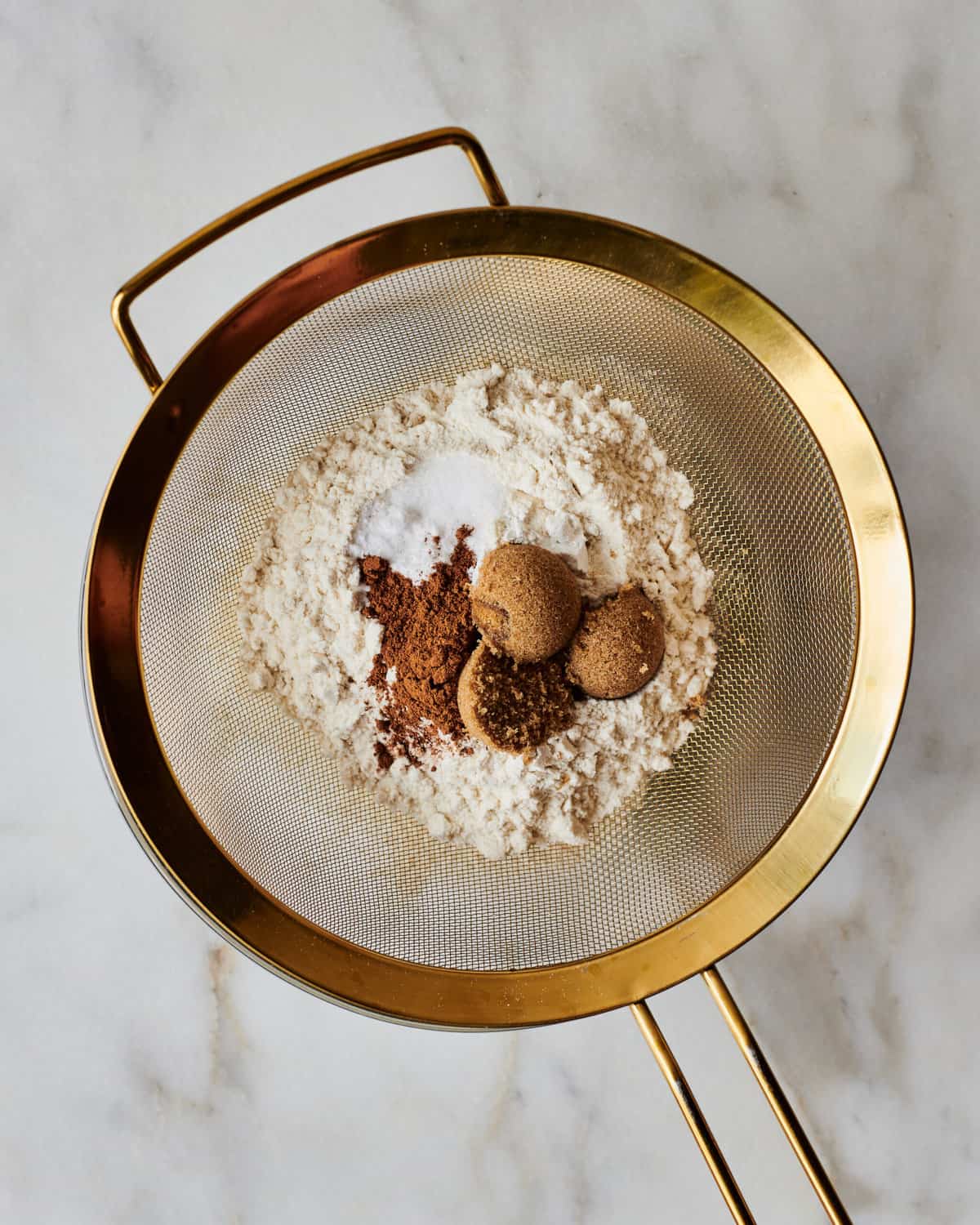 Spices and baking soda being sifted into a bowl.