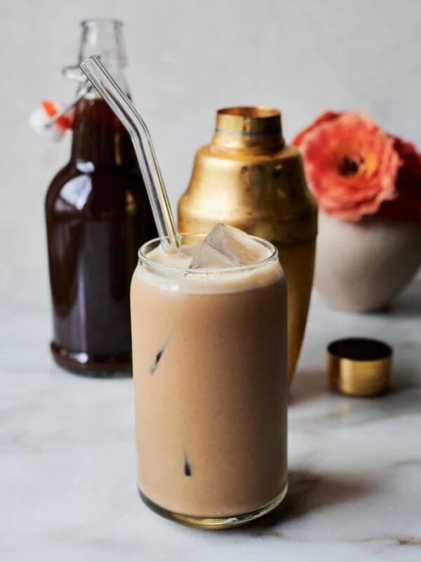 Iced Pumpkin Spice Latte in glass with shaker and pumpkin syrup.