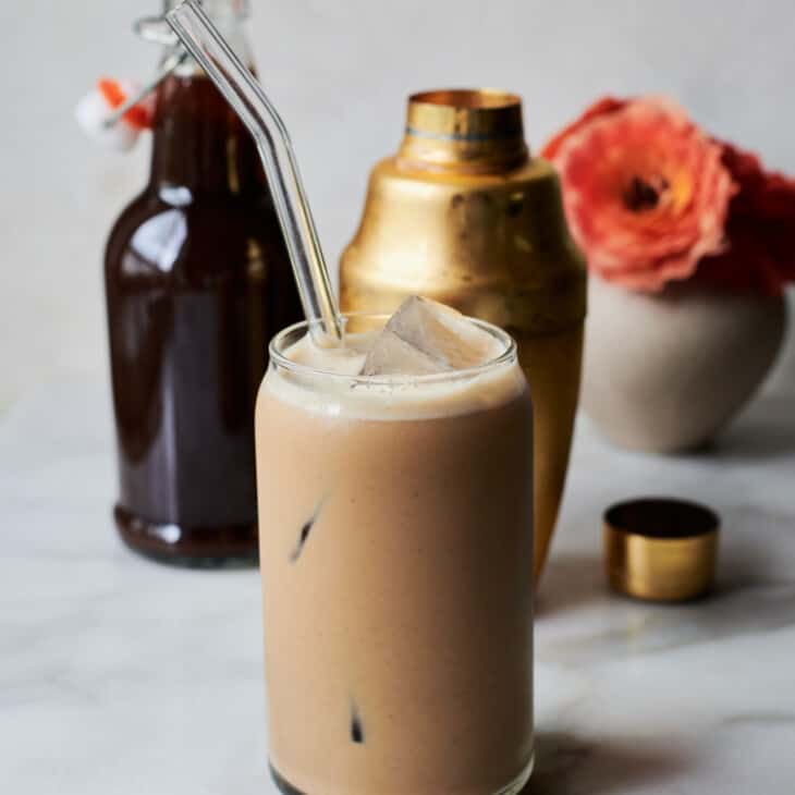 Iced Pumpkin Spice Latte in glass with shaker and pumpkin syrup.