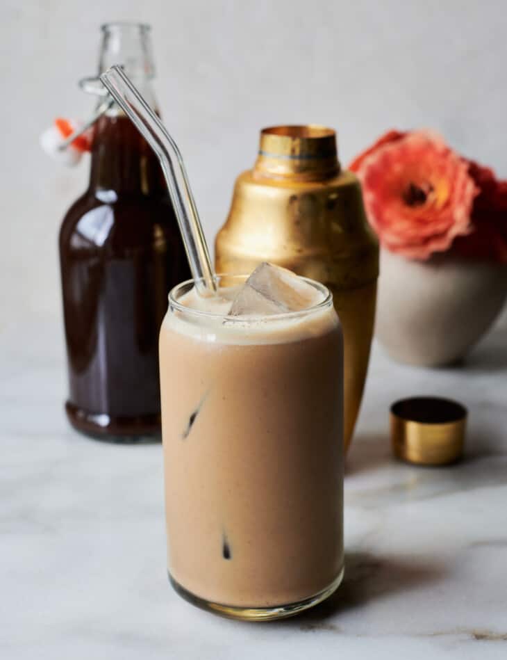 Iced Pumpkin Spice Latte in glass with shaker and pumpkin syrup.