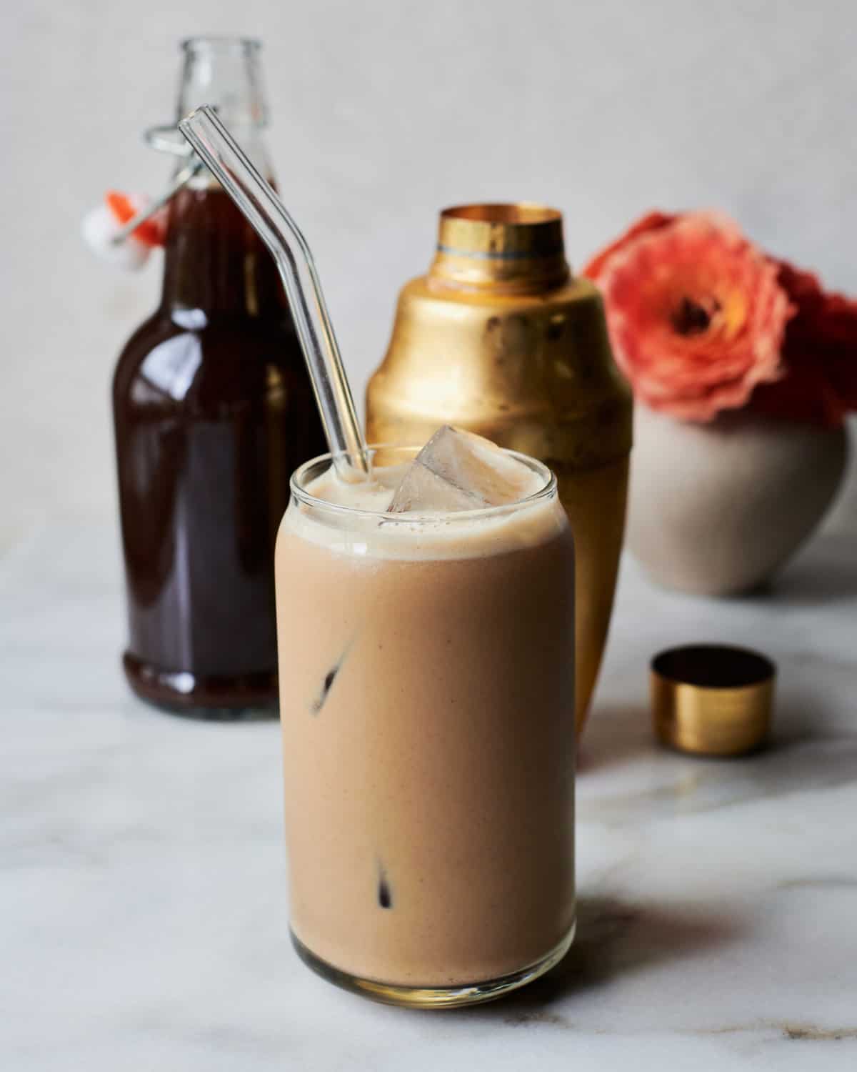 Iced Pumpkin Spice Latte in glass with shaker and pumpkin syrup. 