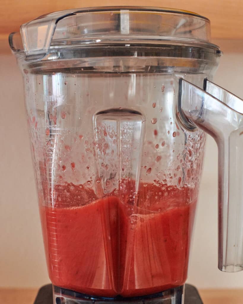 a blender with the strawberry syrup being blended.