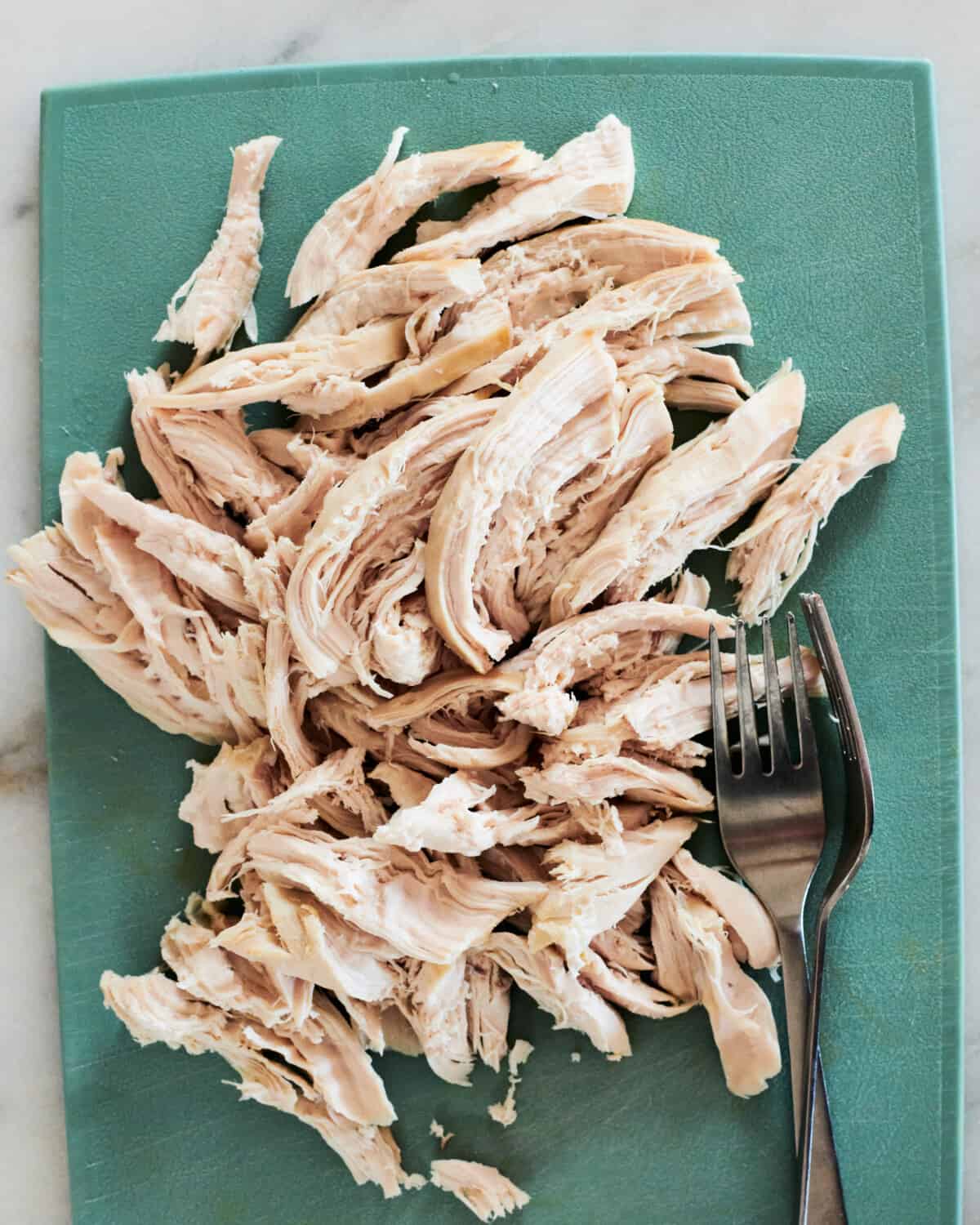 Shredded chicken on a cutting board. 