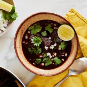 Birria Soup in bowl with lime, onion and cilantro on top.
