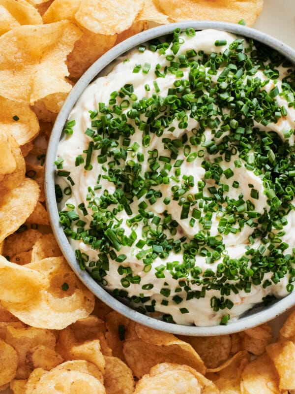 Bowl with shallot dip topped with chives and served with chips.