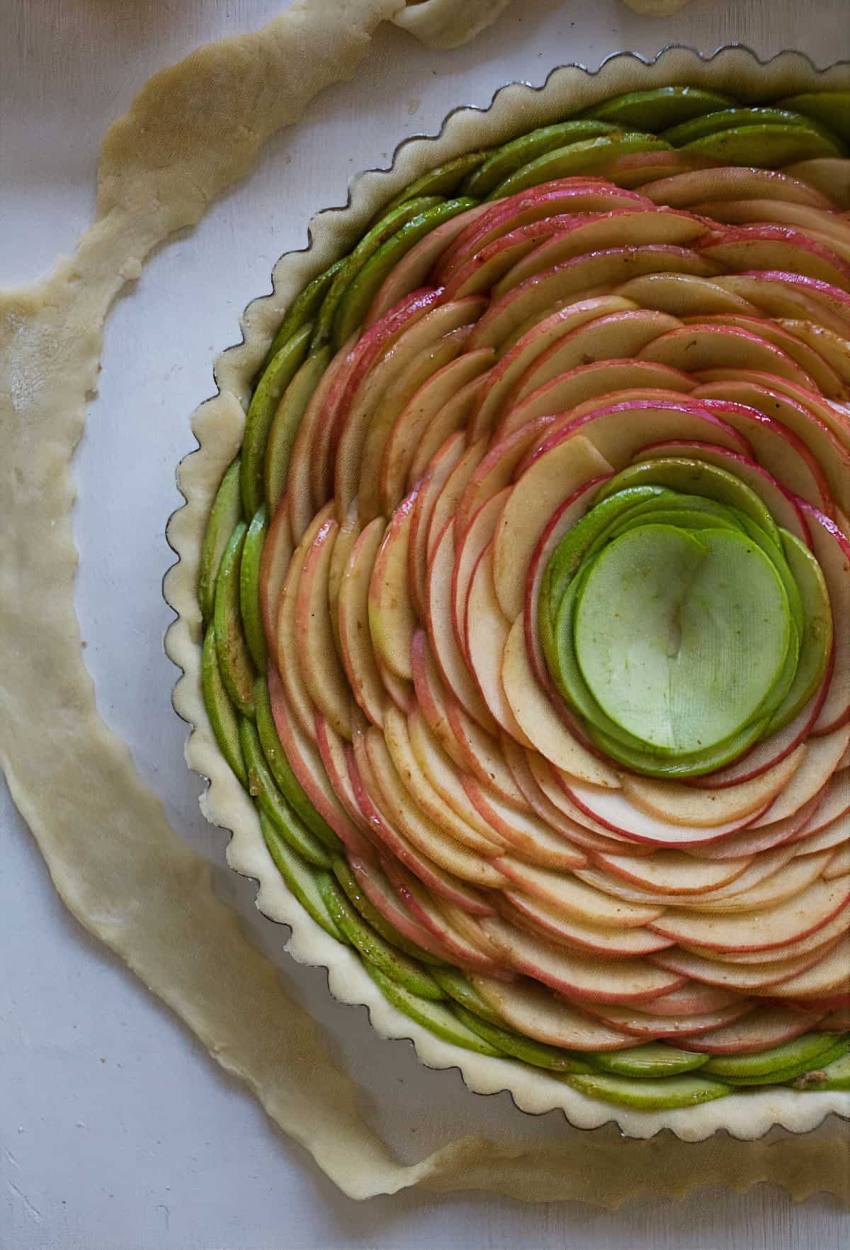 Pie being assembled with apples going all the way around.
