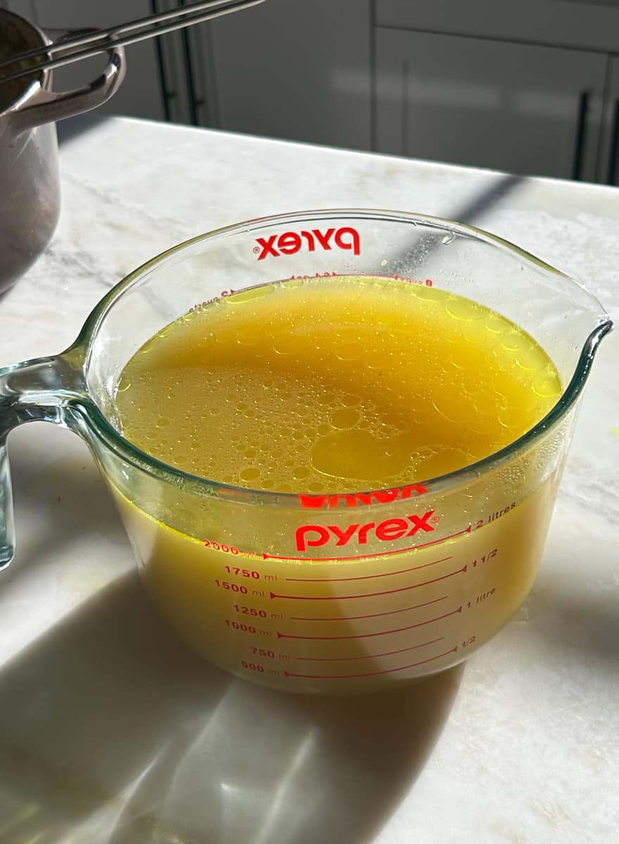 Pitcher of chicken stock after it's been strained.