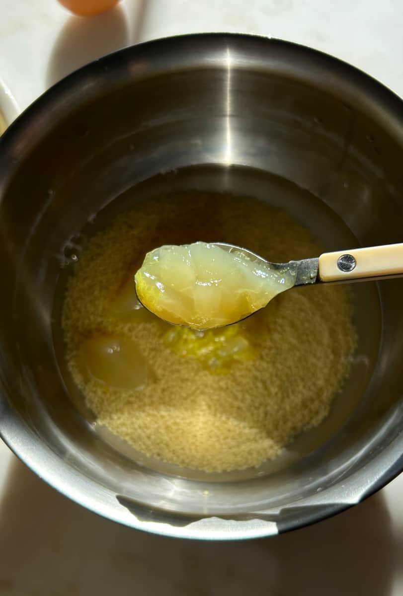 Scoop of chicken stock going in pot.