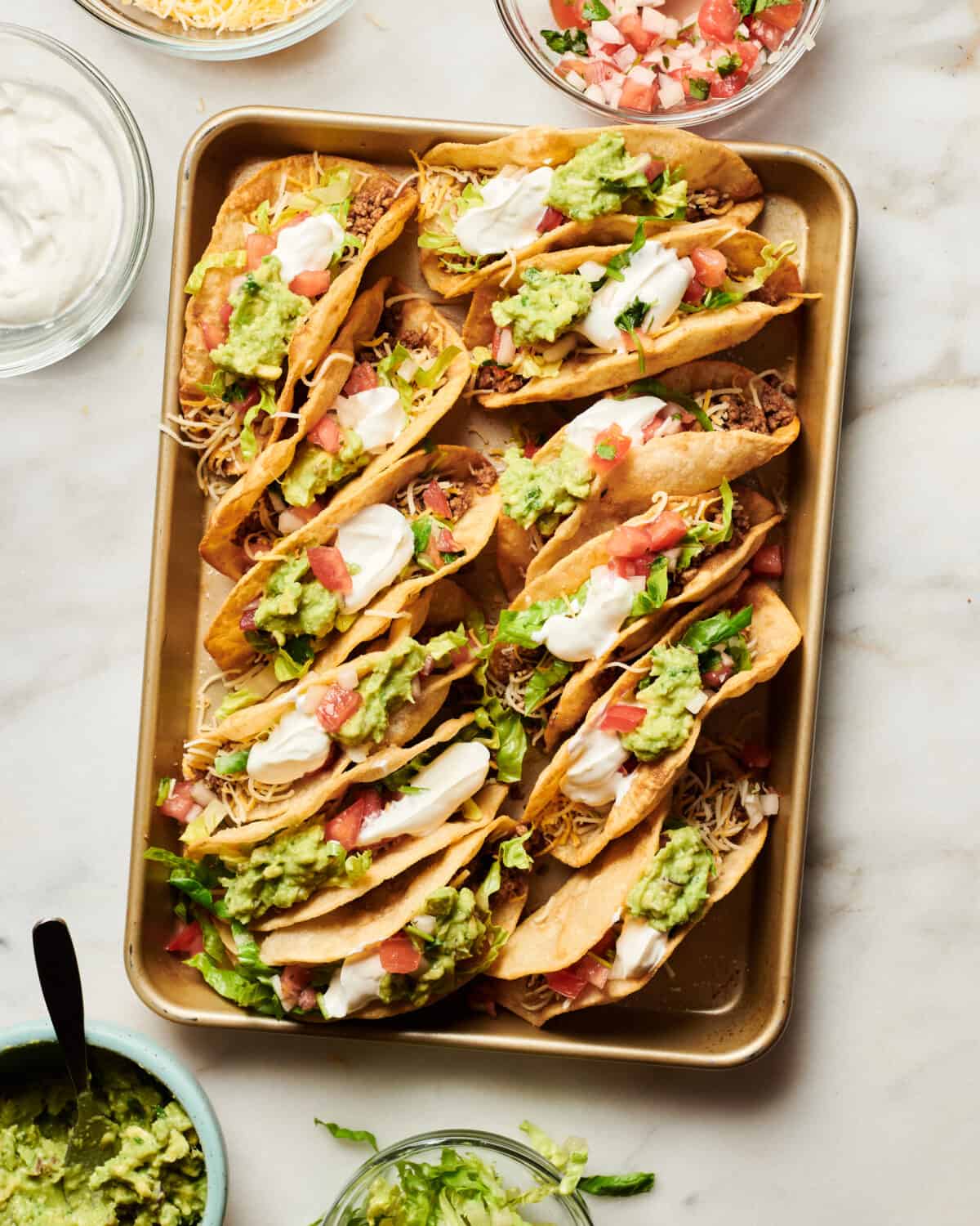 Ground Beef Tacos with sour cream, cheese, pico de gallo and guacamole on top. 