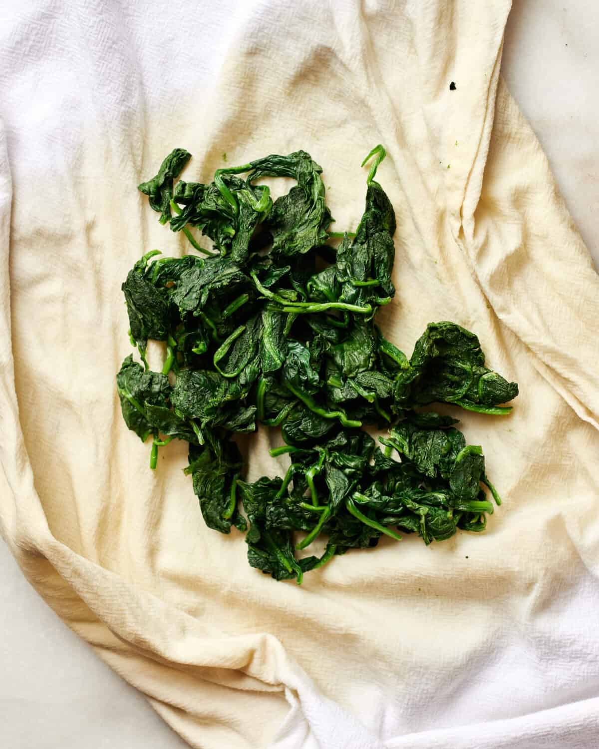 Spinach being wringed out in a paper towel. 
