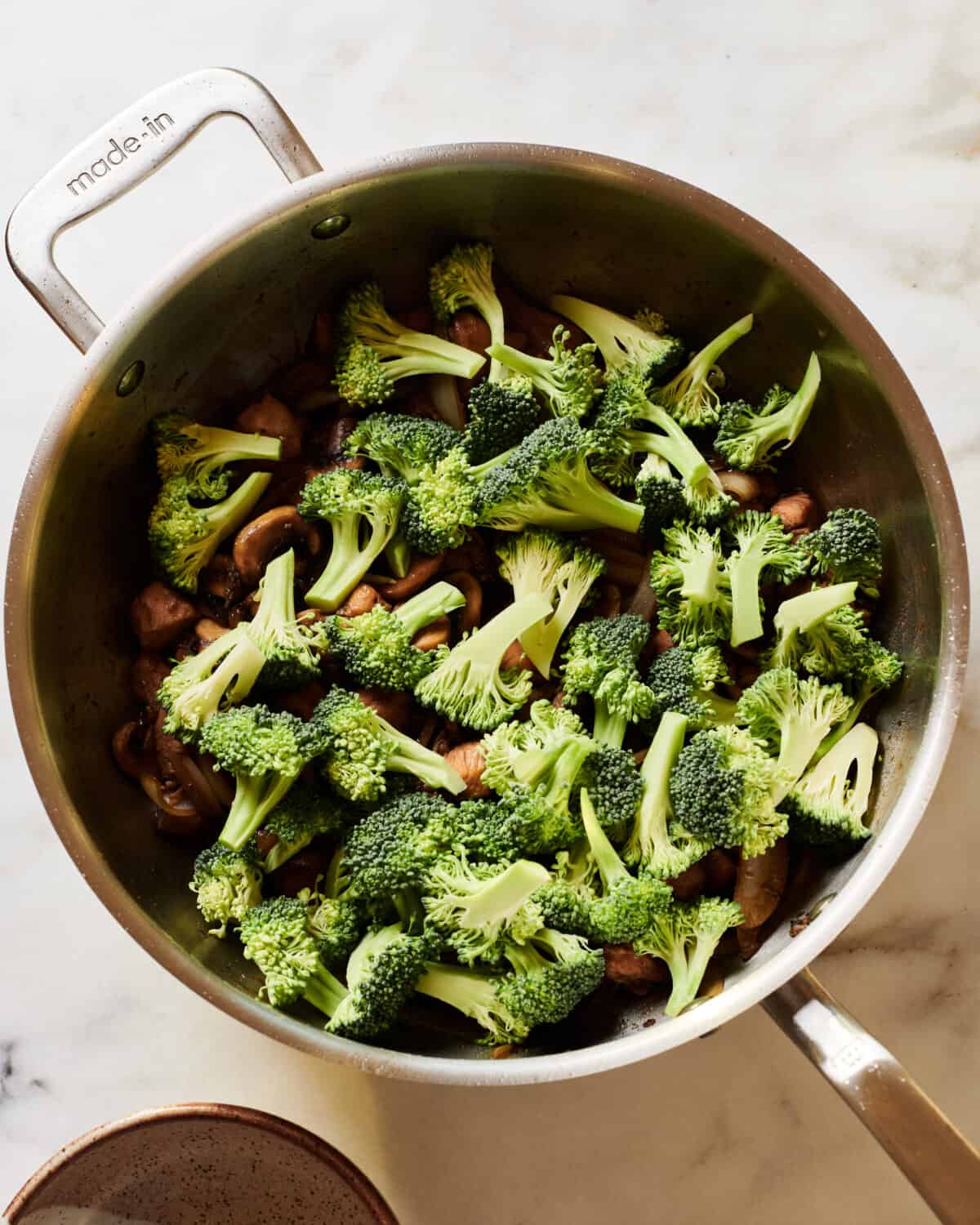 Broccoli being added to pan with the stir-fry.