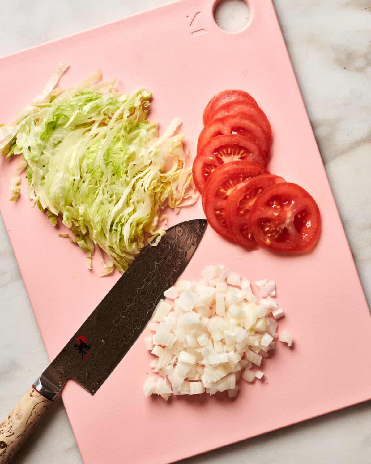 Lettuce, tomato and onion on a cutting board. 