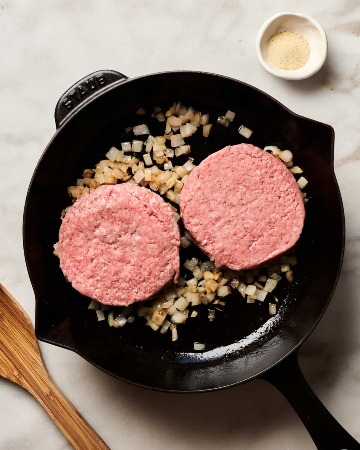 Meat patties cooking in a cast iron skillet. 