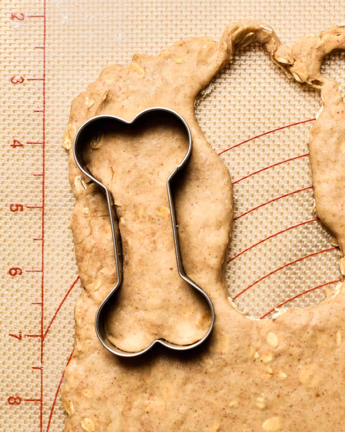 Dog treats being cut out with bone cookie cutter. 