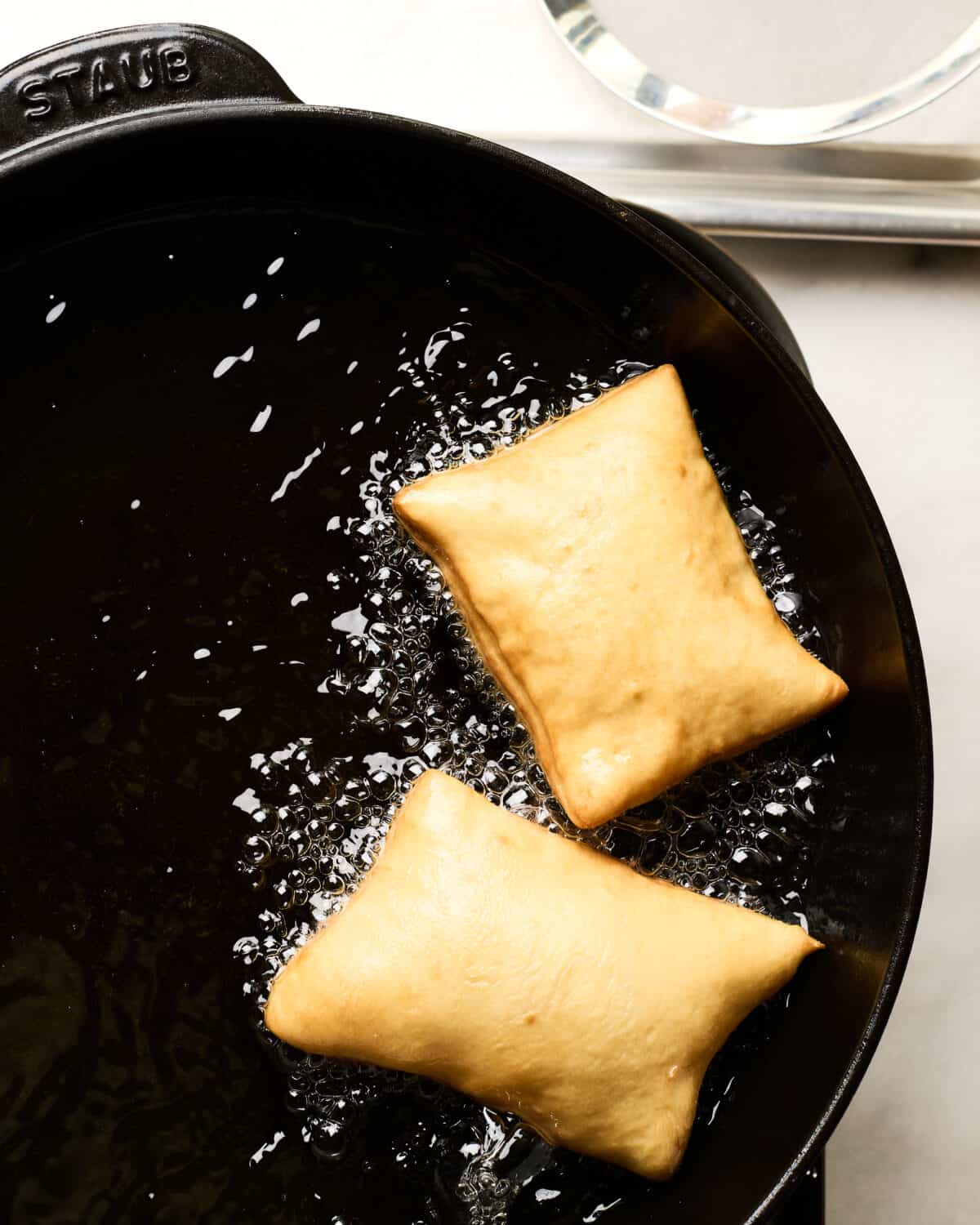 Sopapillas all puffed up in hot oil. 