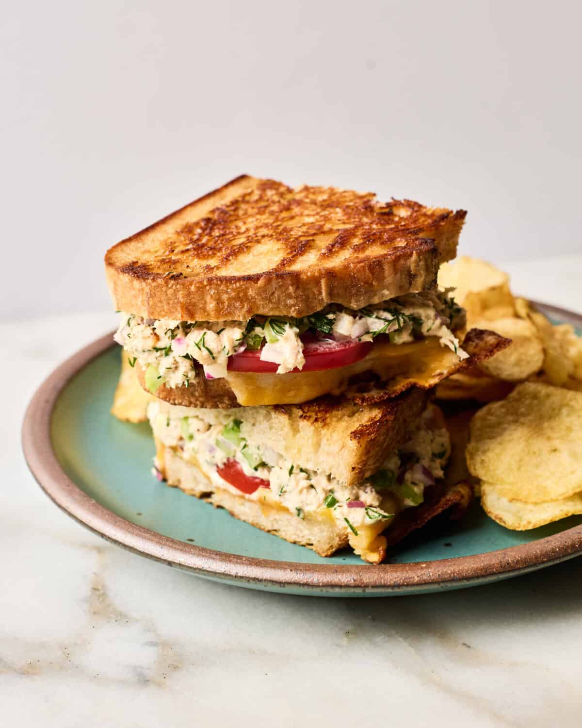 Tuna melt on a plate with chips. 