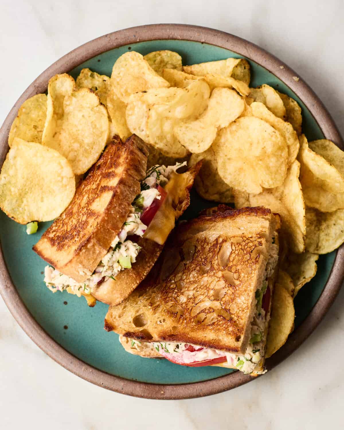 Tuna melt on a plate with chips. 