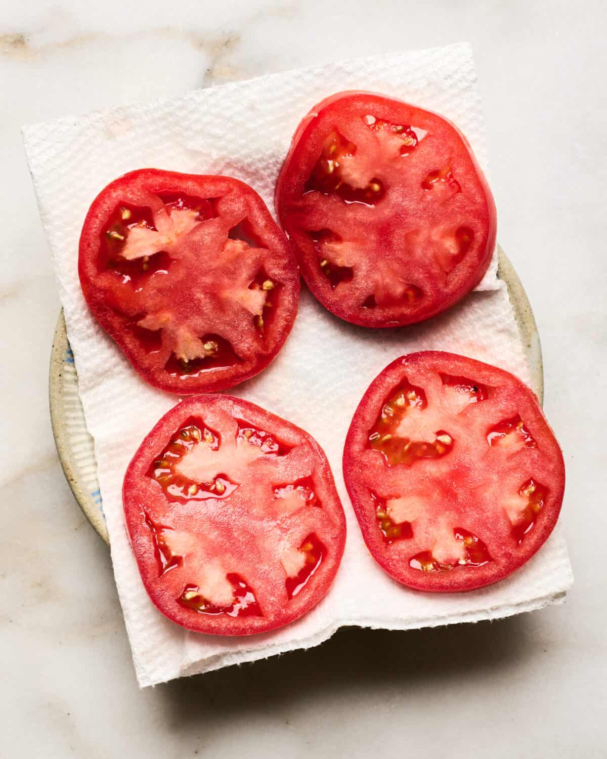 Tomato slices on a bed of paper towels. 