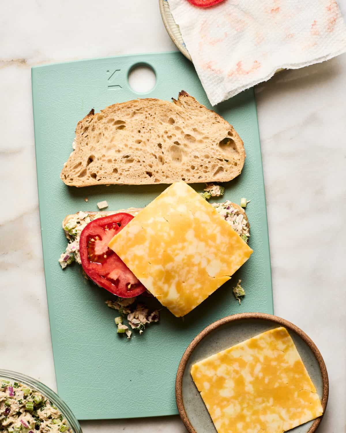 Tuna melt being assembled on a cutting board. 