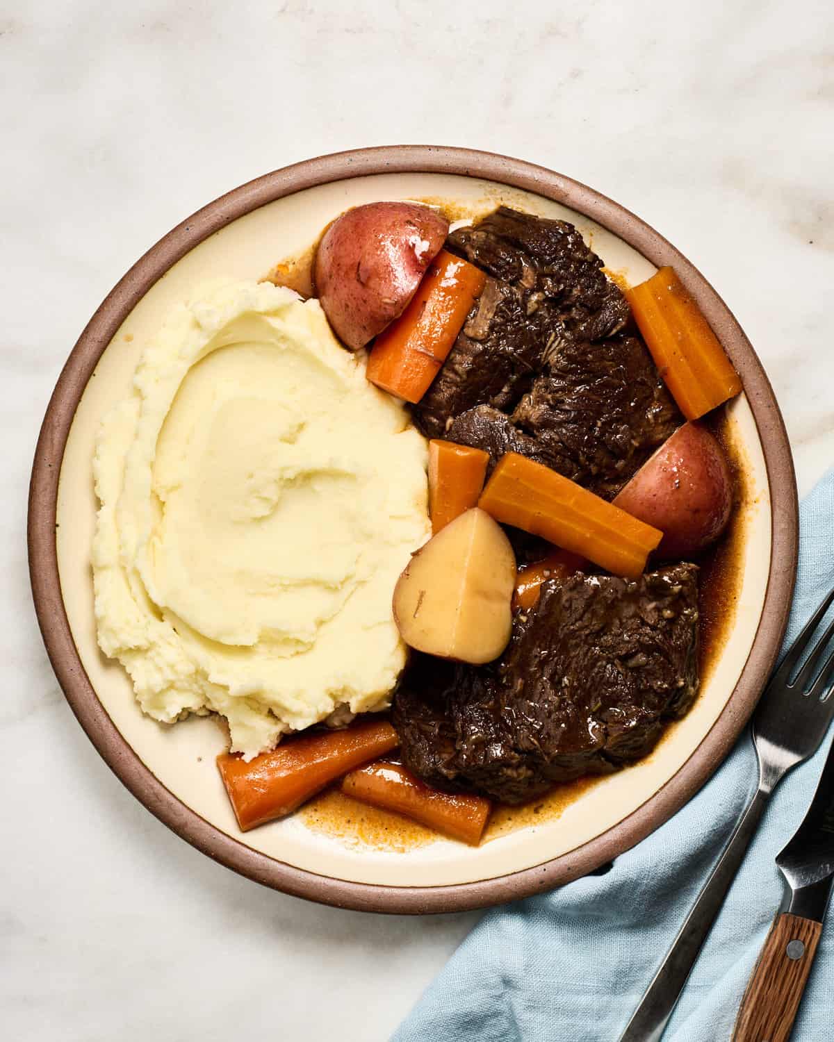 Pot Roast on a plate with mashed potatoes and carrots.