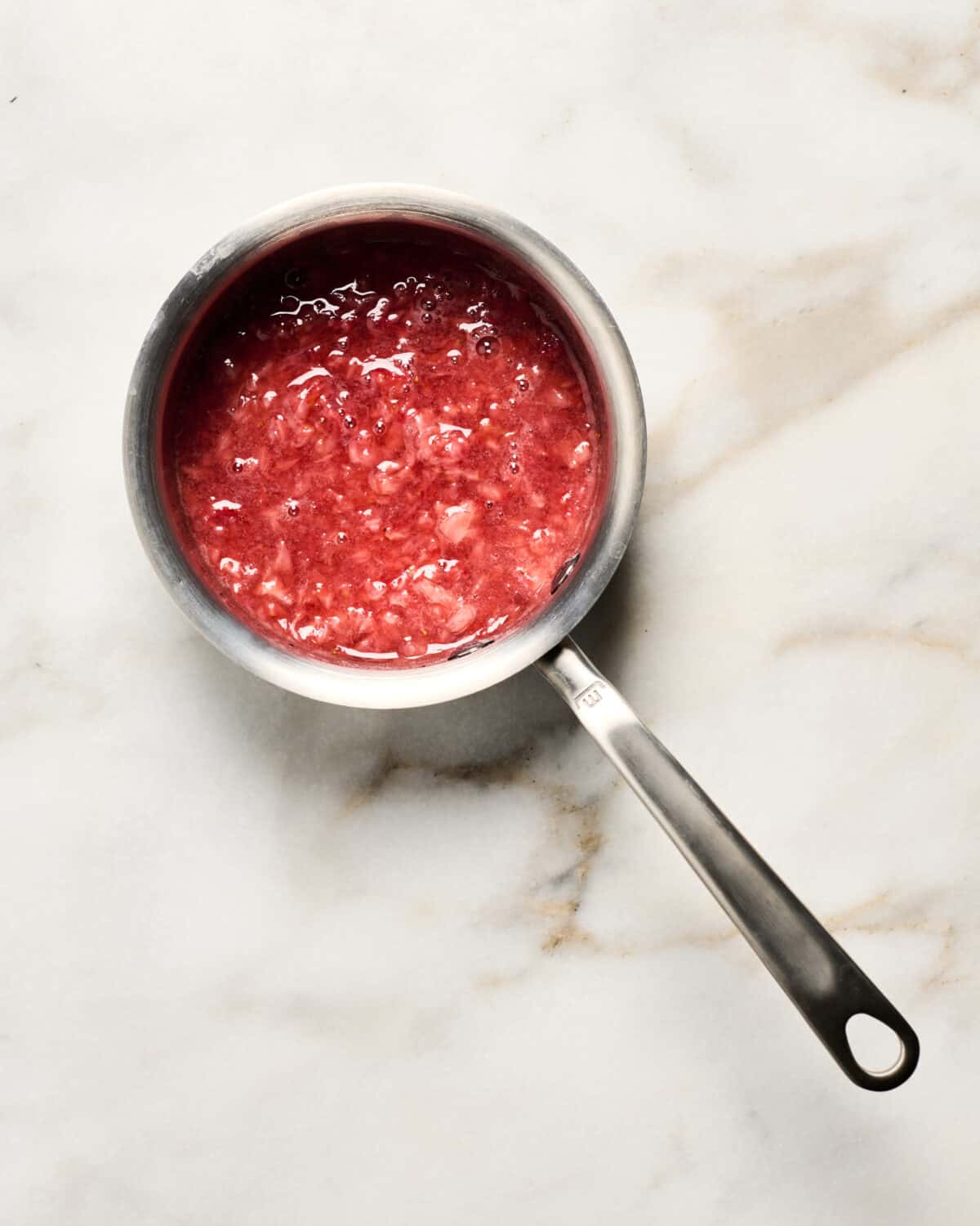 Cooking the strawberry glaze in pan. 